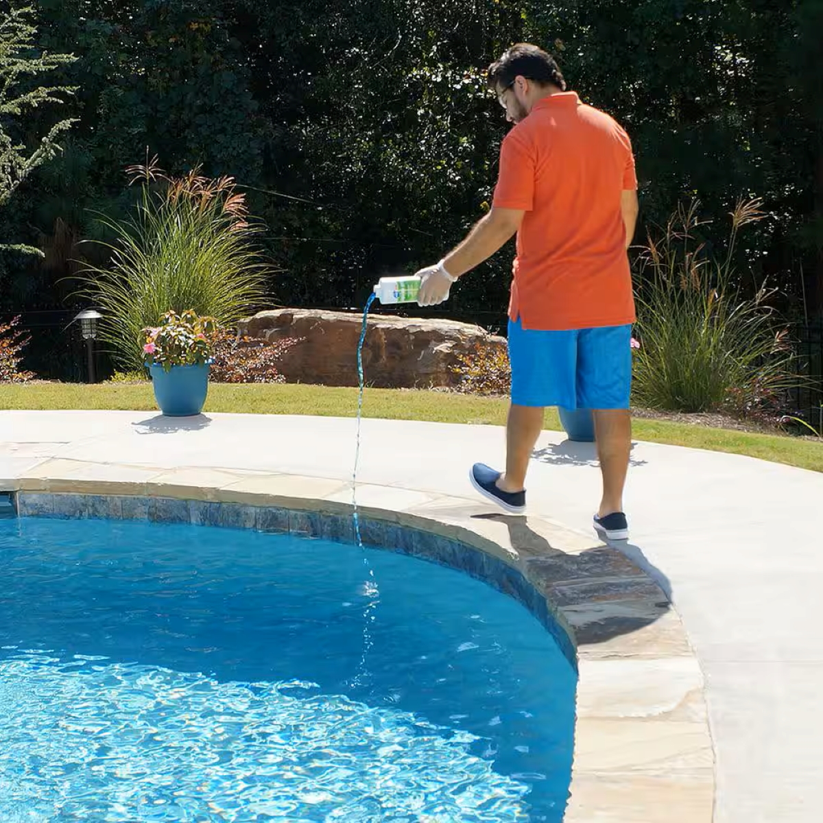 A man is pouring algaecide in their swimming pool.