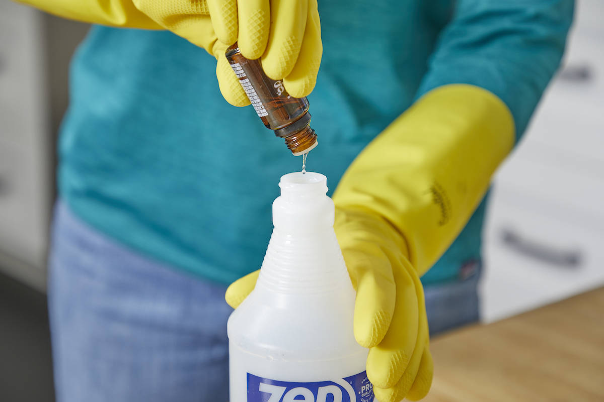 Woman adds drops of essential oil to a spray bottle.