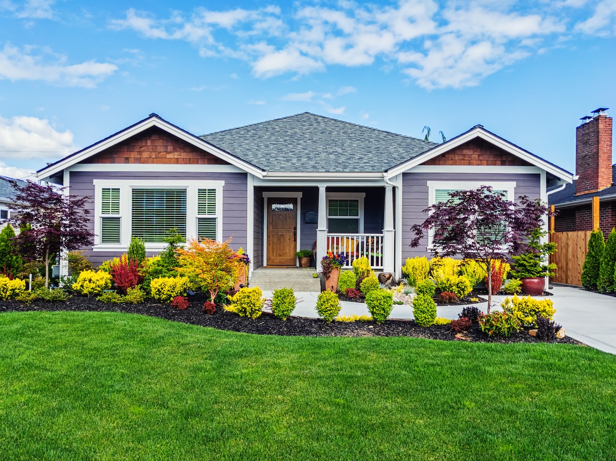 A modern single-level home with green lawn and nice landscaping.