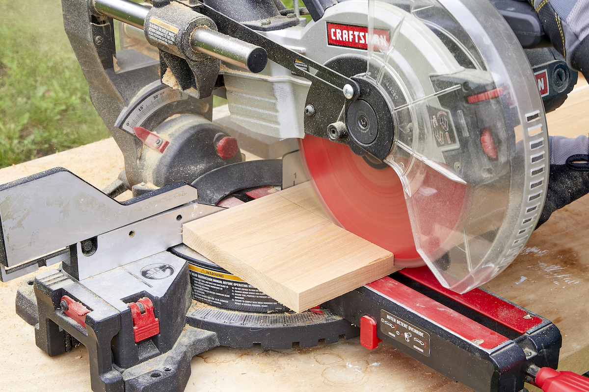 Person uses a miter saw to cut a piece of wood.