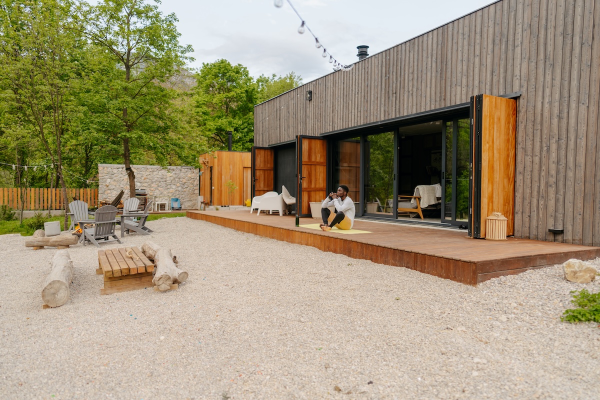 Man sitting on modern style deck that overlooks gravel patio with stylish deck furniture.