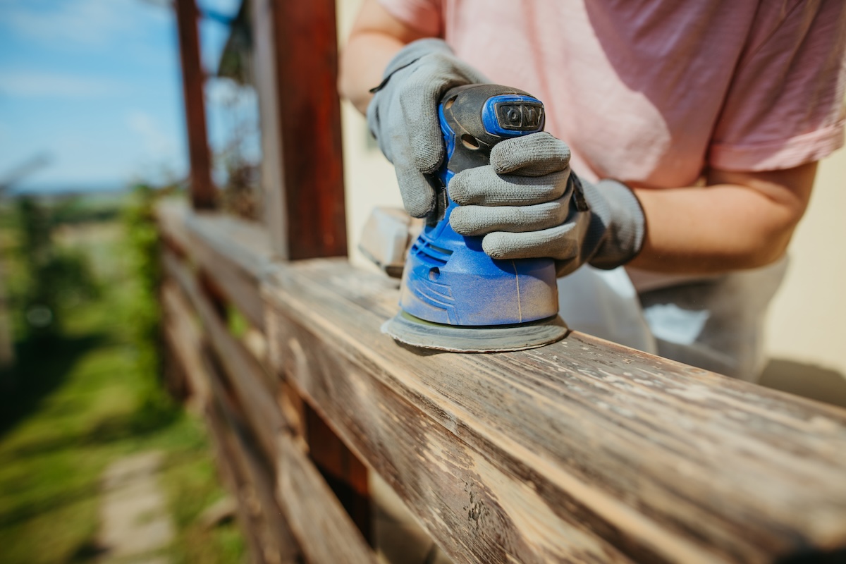 Using a sander on outdoor deck railings.