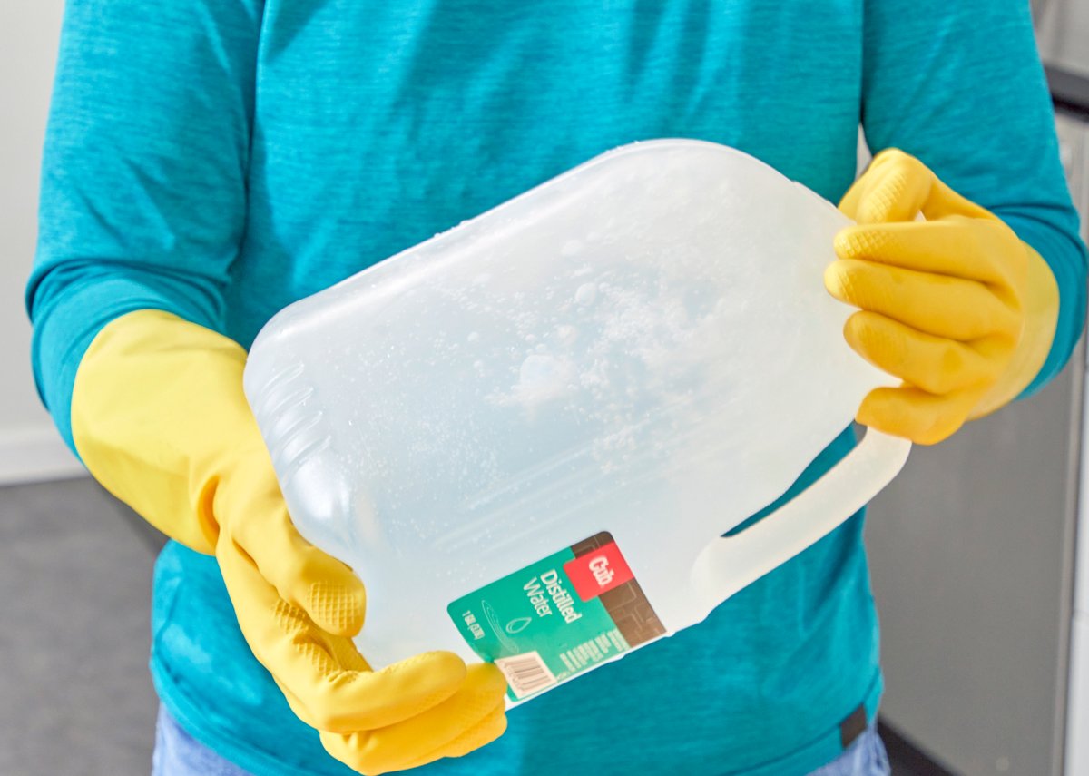 Woman shakes a gallon of distilled water.