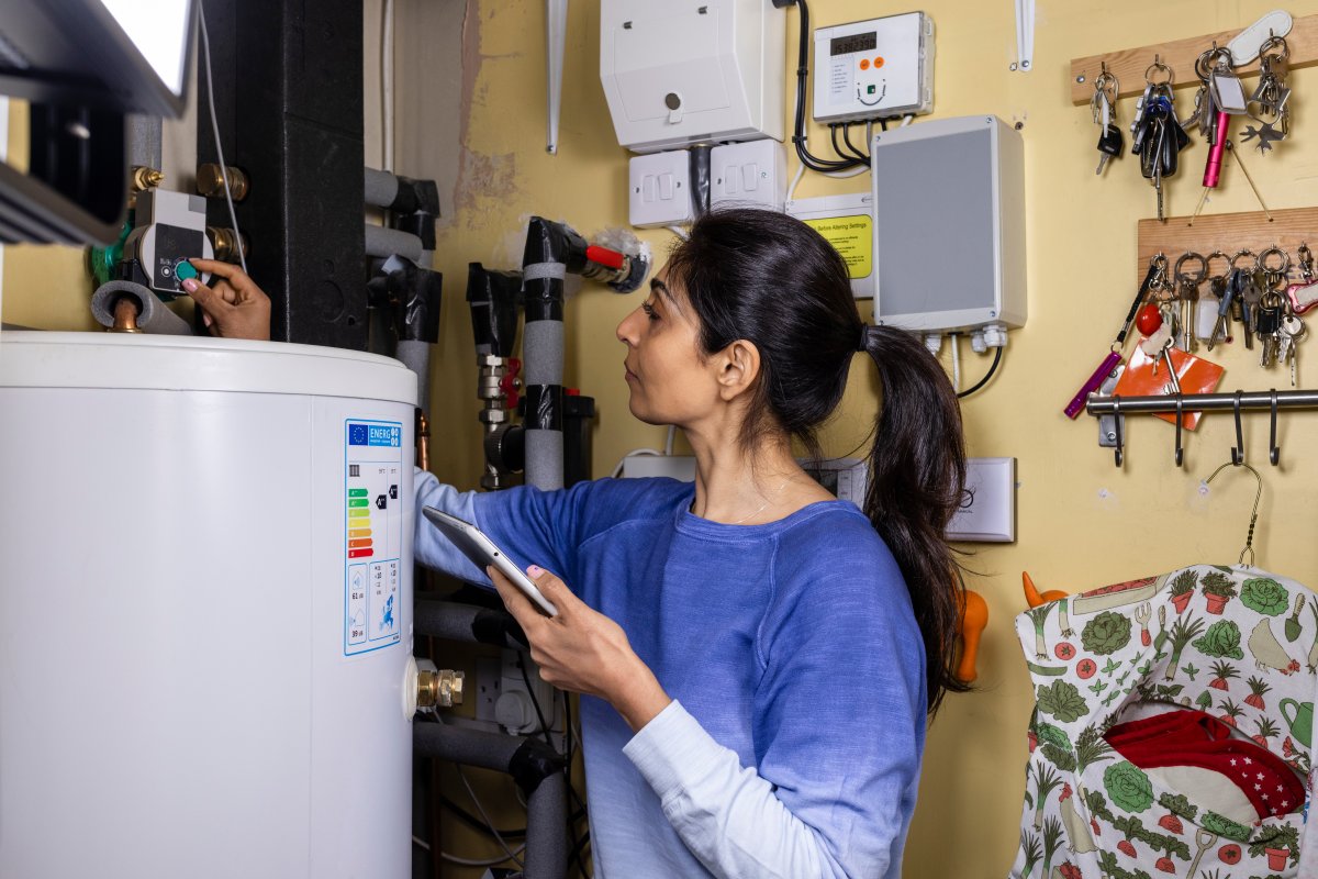 Woman in blue sweater examines her home hot water tank system.