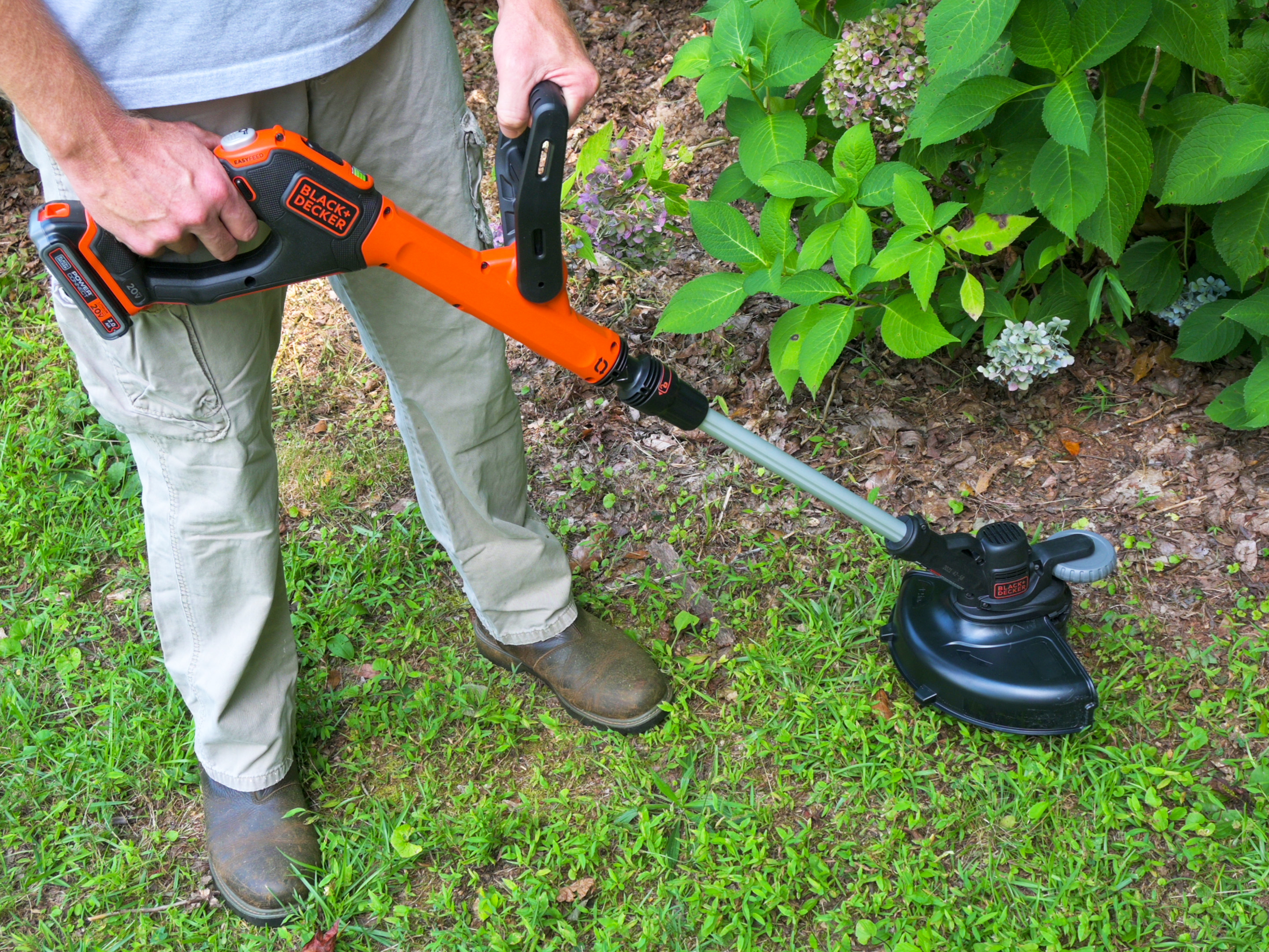 A Bob Vila writer tests out the Black+Decker 20V Max EasyFeed String Trimmer/Edger on weeds in the lawn