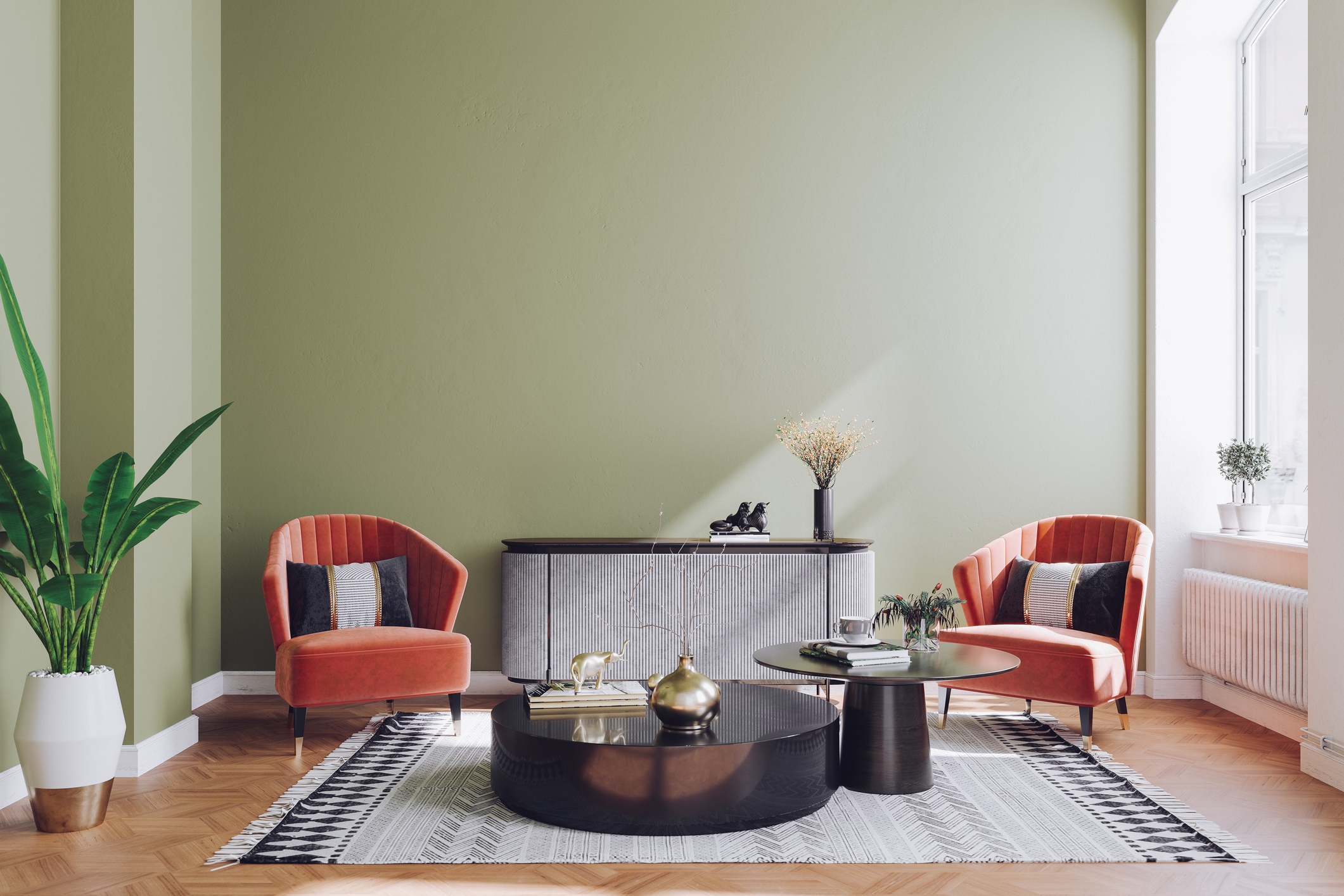 A spacious sitting room with mid-century modern decor features two red chairs, two coffee tables, and a console table along the back wall.