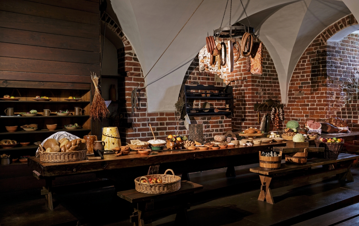 A large kitchen with a long table full of different cured meats, bread and cheeses.