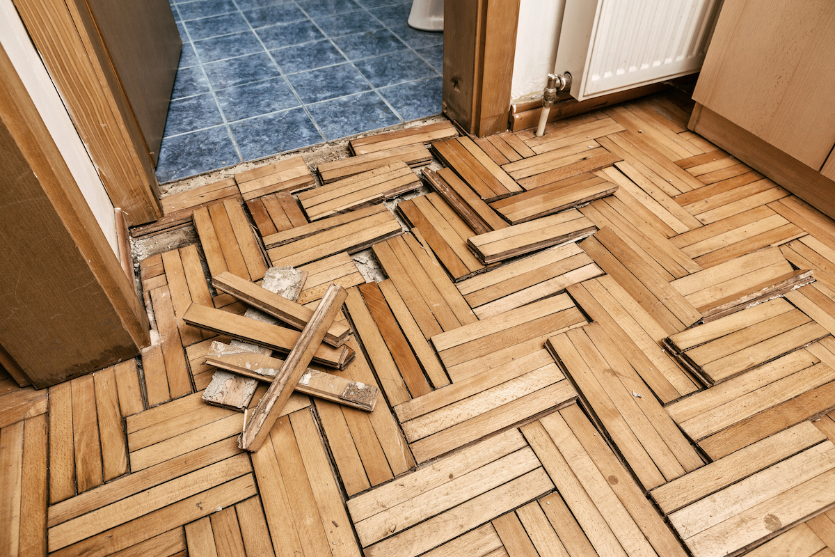 Wooden flooring in a bathroom is warped and damaged from humidity.