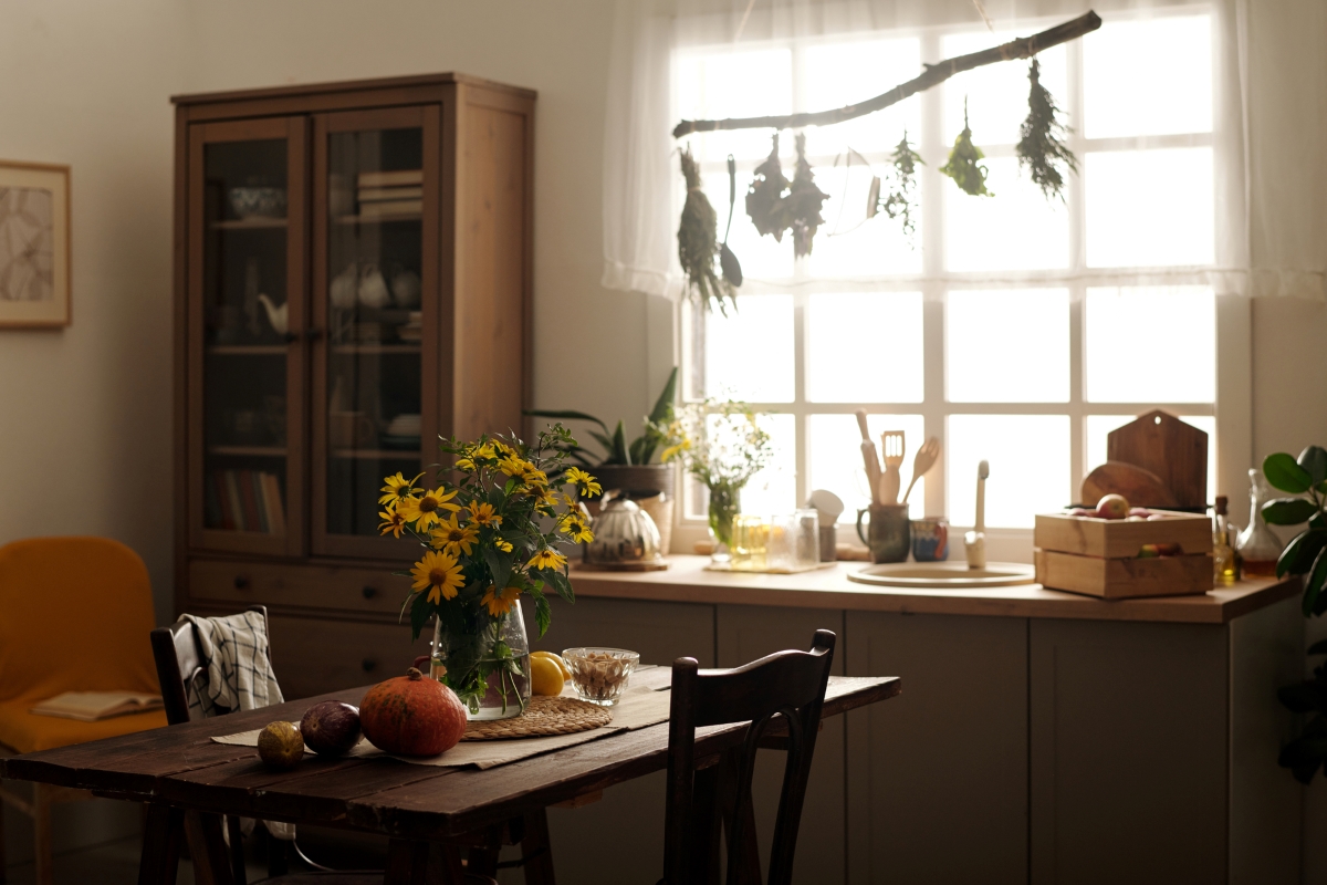 A small vintage kitchen with yellow daisy flowers on the table.