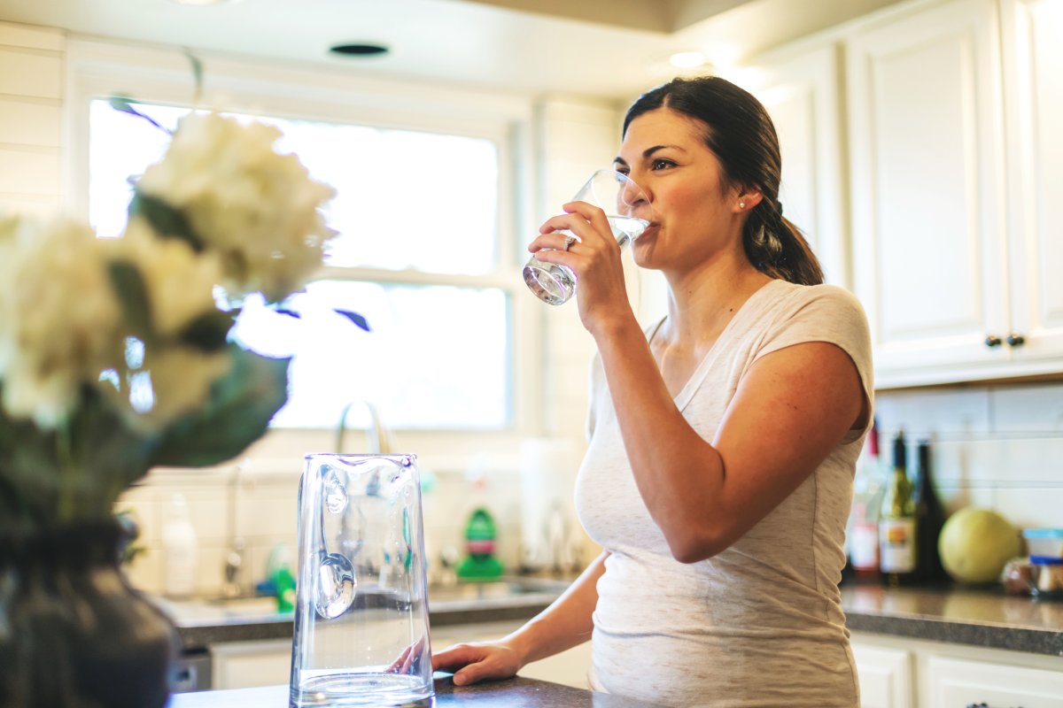 Woman drinking water out of a glass in her home.