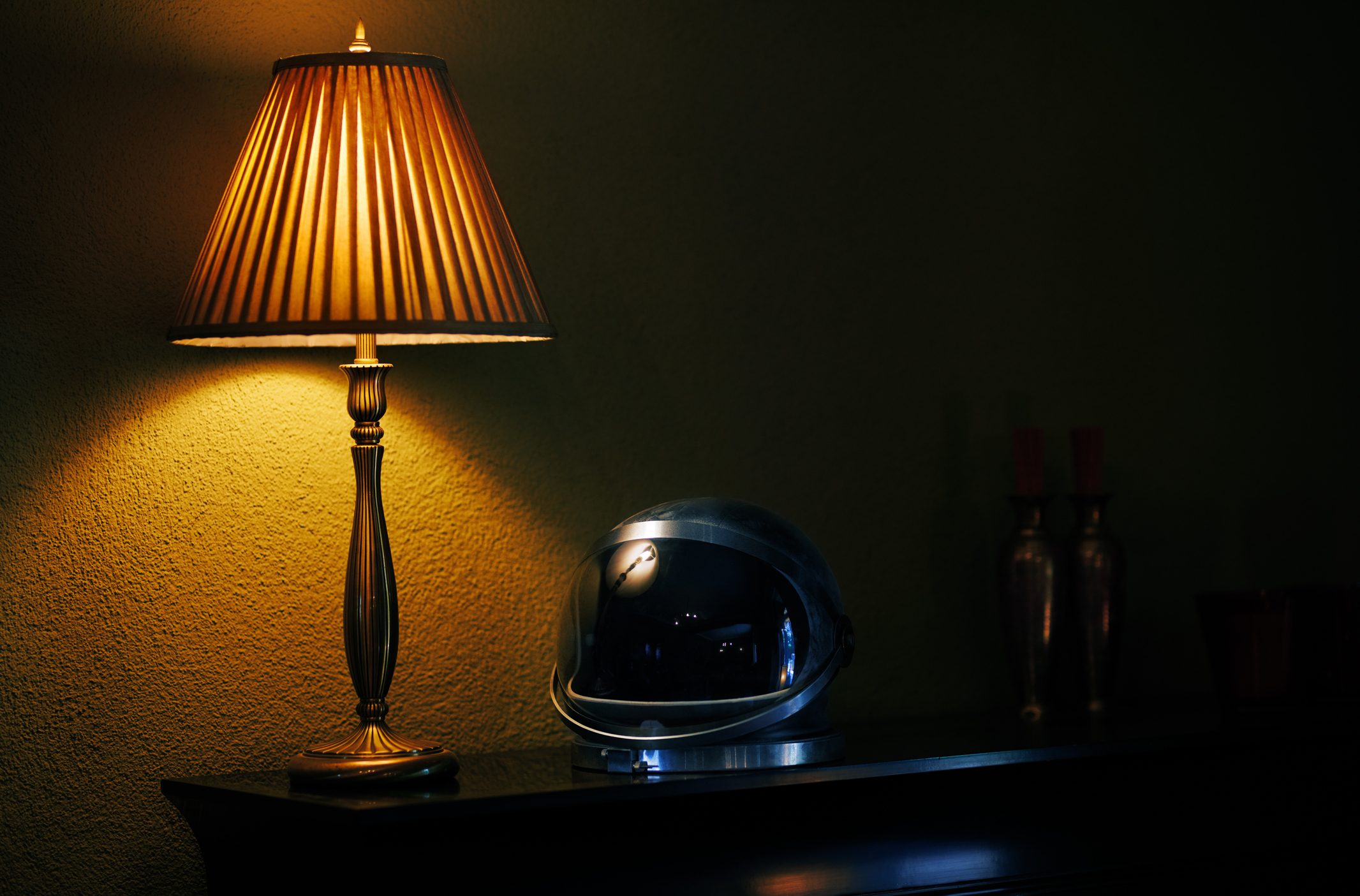 A lamp with dimmer is softly glowing amber on a bedside table