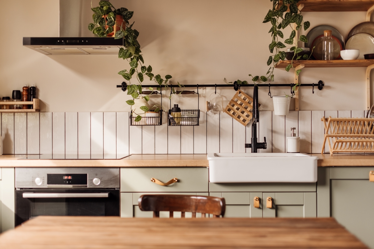 A warm kitchen with green cabinets and kitchen island.