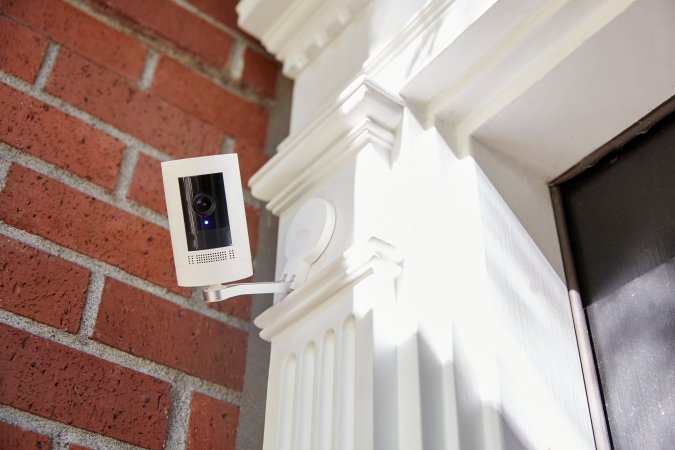 An outdoor security camera mounted on a brick home..