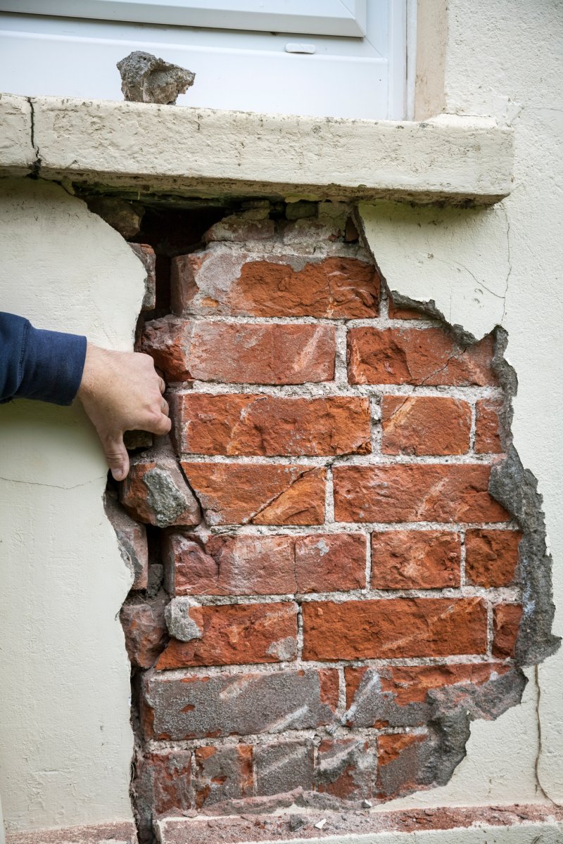 Surveyor examines a large crack in a brick building wall.