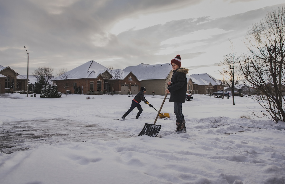 Two brothers shoveling the driveway after a light snowfall.