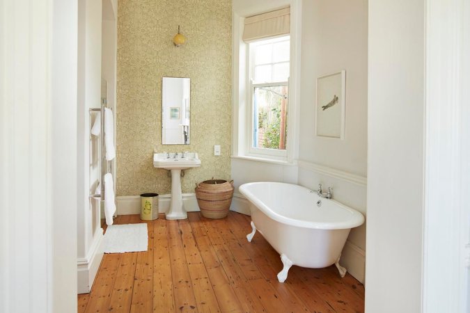 Wood flooring is seen in a bathroom.