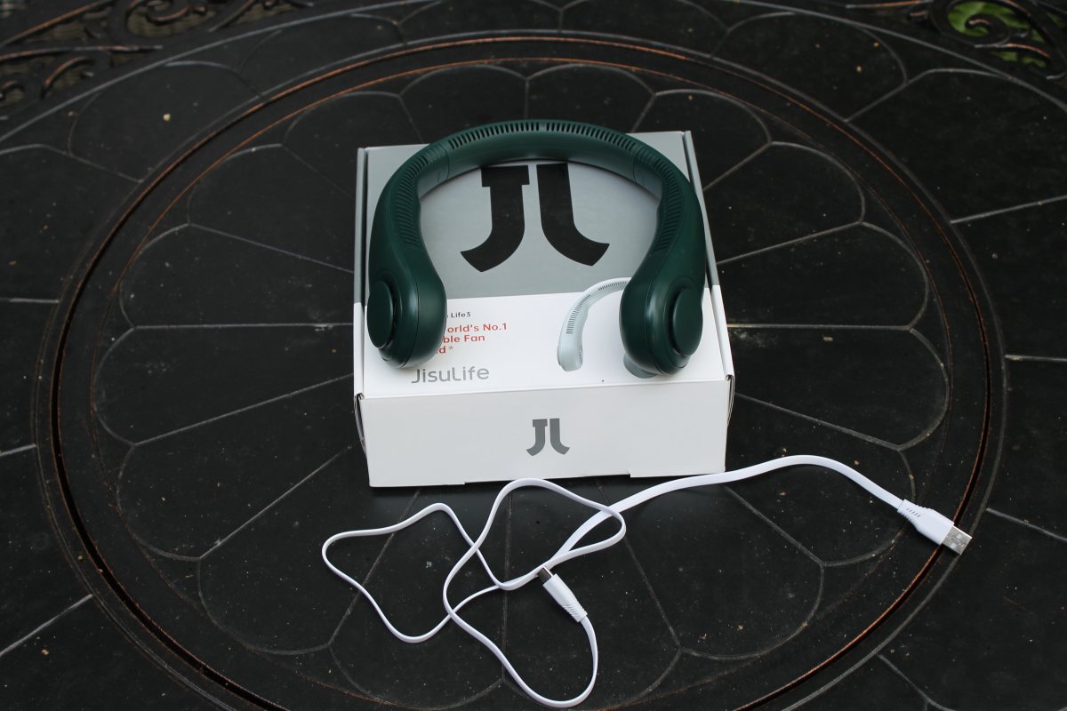 Green Jisulife Portable Neck Fan on top of its box with charging cord