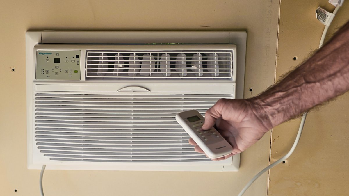 Person using a remote to control a through-the-wall garage air conditioner