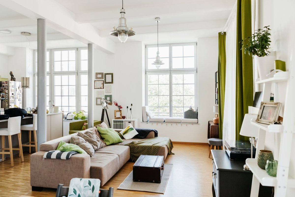 A modern living room in an open-plan home is decorated with a colorful earthy color scheme of greens and neutrals.