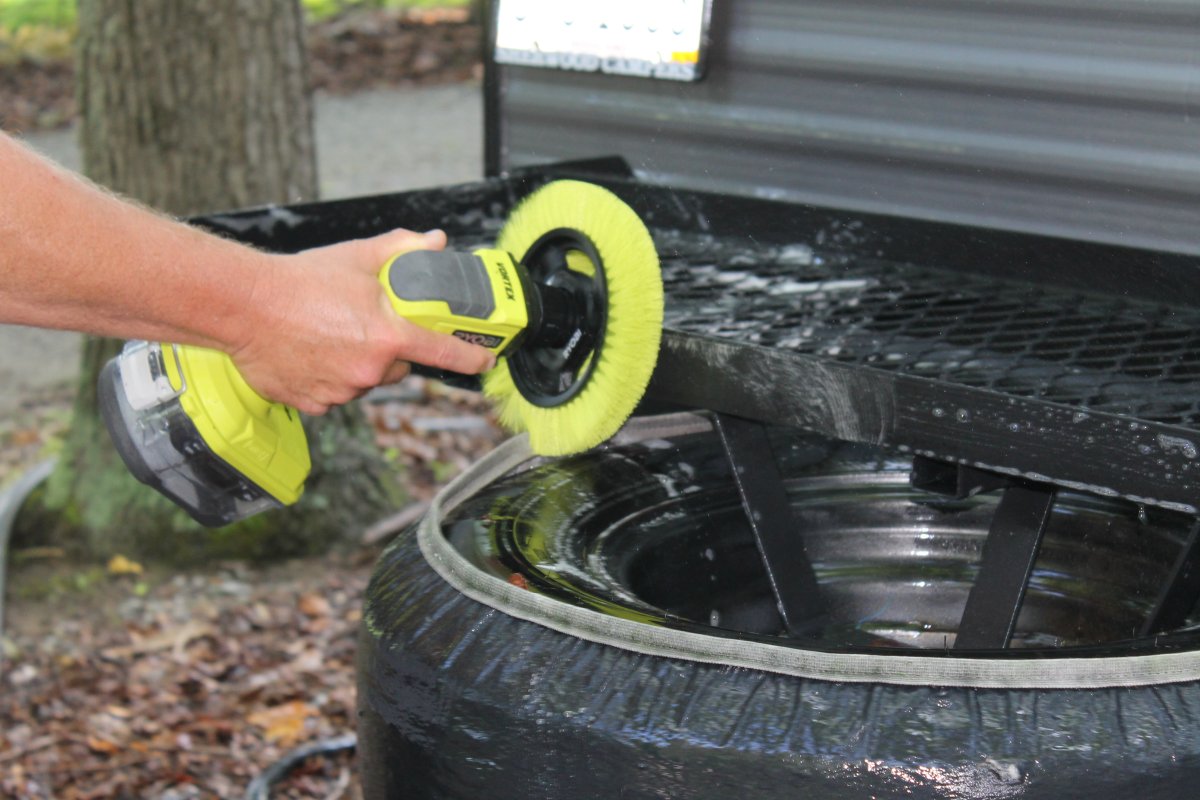 Person using Ryobi Power Scrubber to clean back of camper