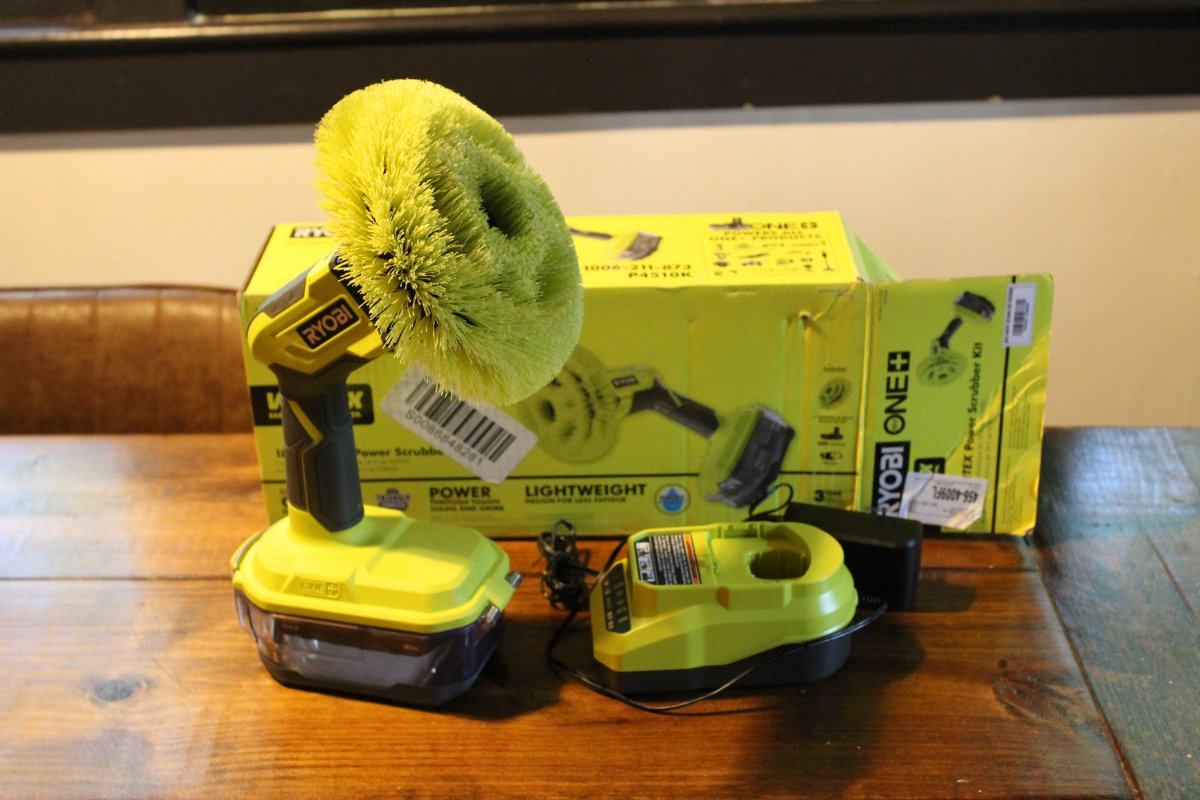 Ryobi One+ 18V Power Scrubber sitting on table next to charger and box