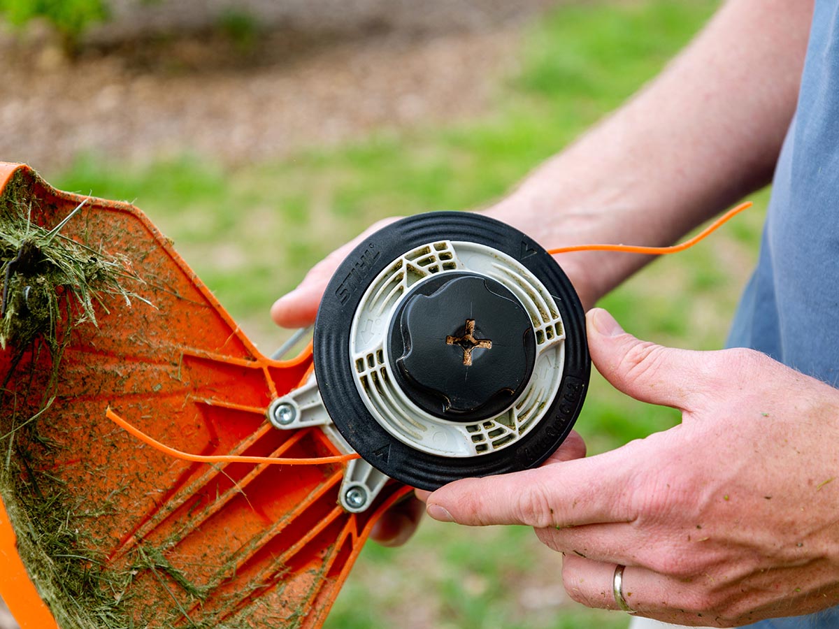 Person holding a spool of weed eater string on Stihl FSA 80 R Battery Trimmer