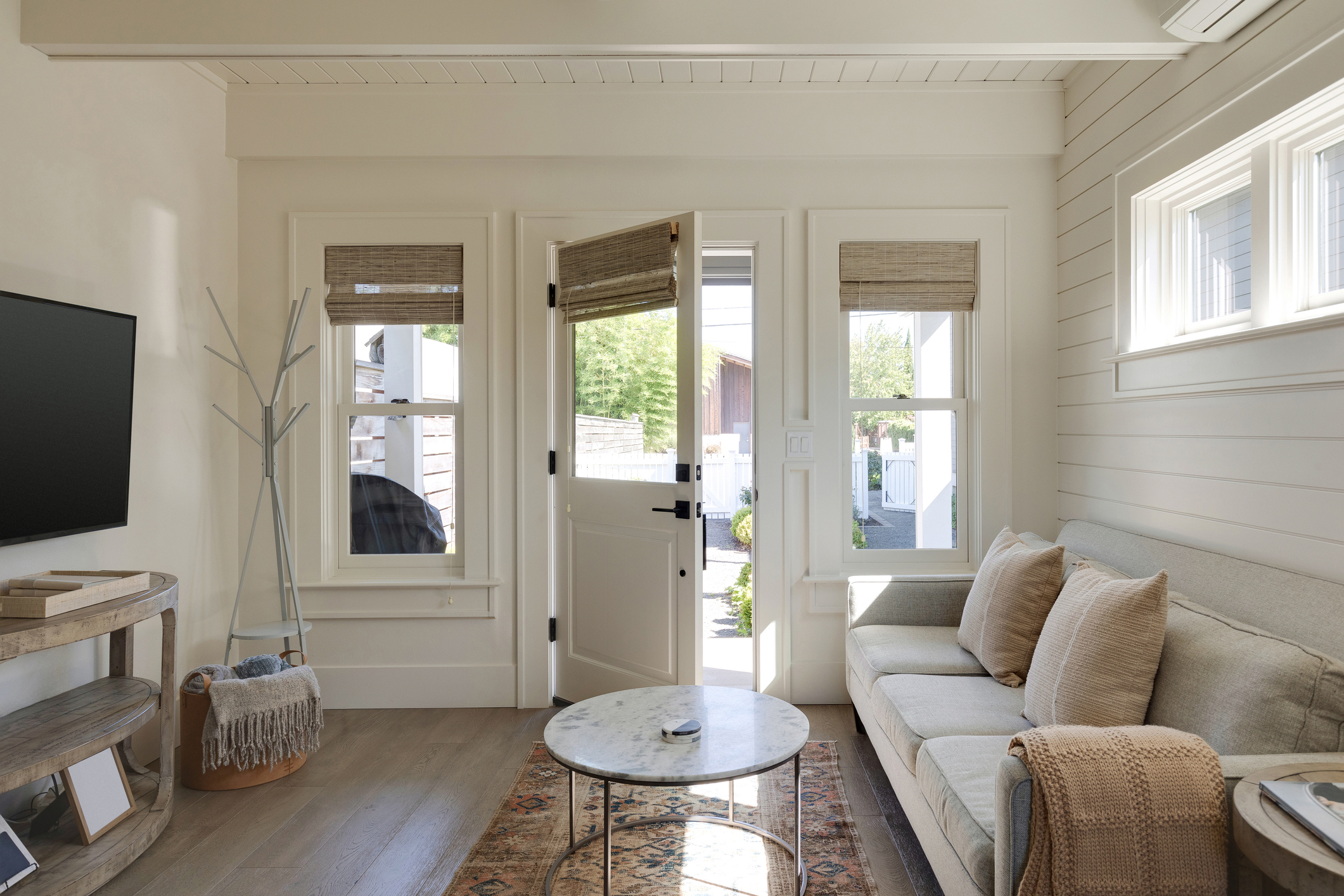 The front entrance and family room of a cottage in Carlton, Oregon. The front door is ajar, letting natural light into the room.