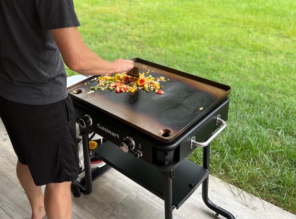 Person cooking fajita veggies on a Cuisinart outdoor griddle