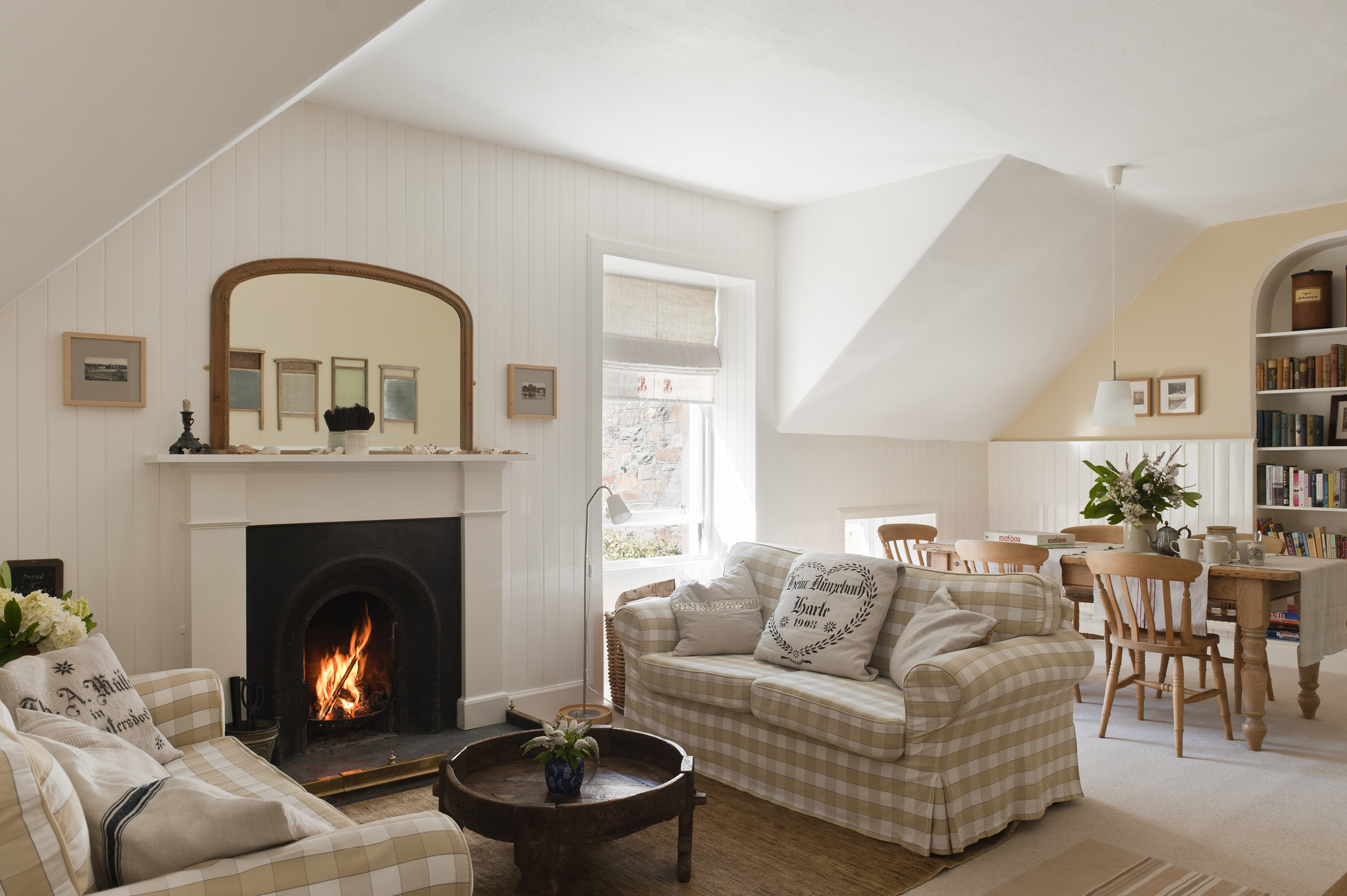 Two matching gingham cream-and-white sofas face each other next to the fireplace in an open-plan living area.