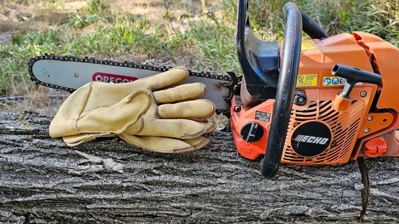 Vermont work gloves on a log next to an orange Echo chainsaw