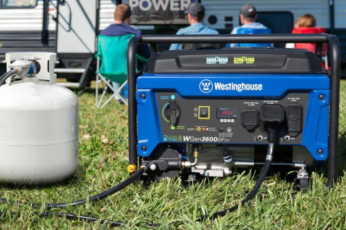 A Westinghouse 3600-Watt Gasoline/Propane Portable Generator connected to a small propane tank is being used to power a TV under an RV's awning.