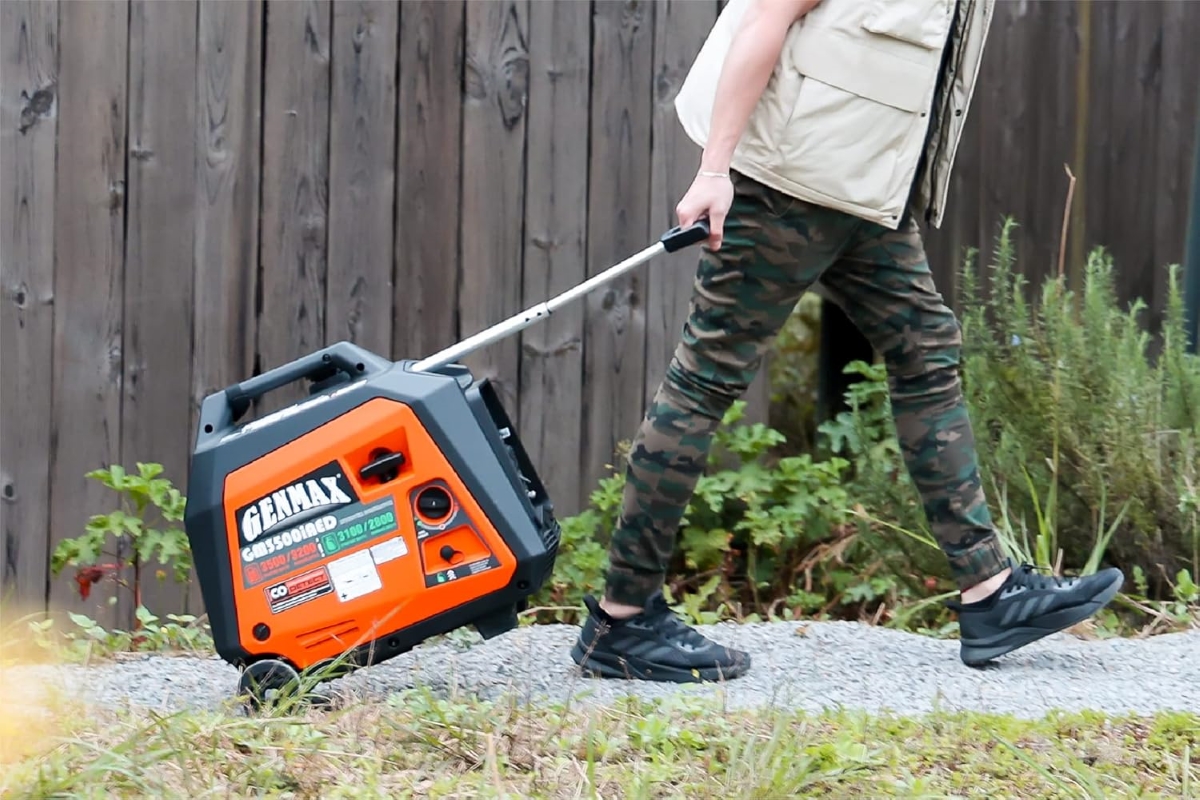 A person is rolling a portable inverter generator with a handle.