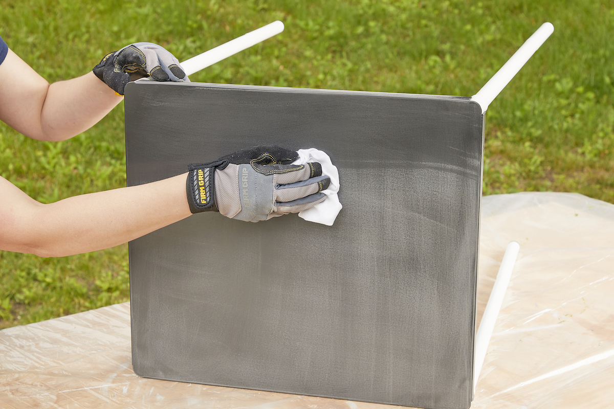 Woman wipes sanded metal with a clean rag.