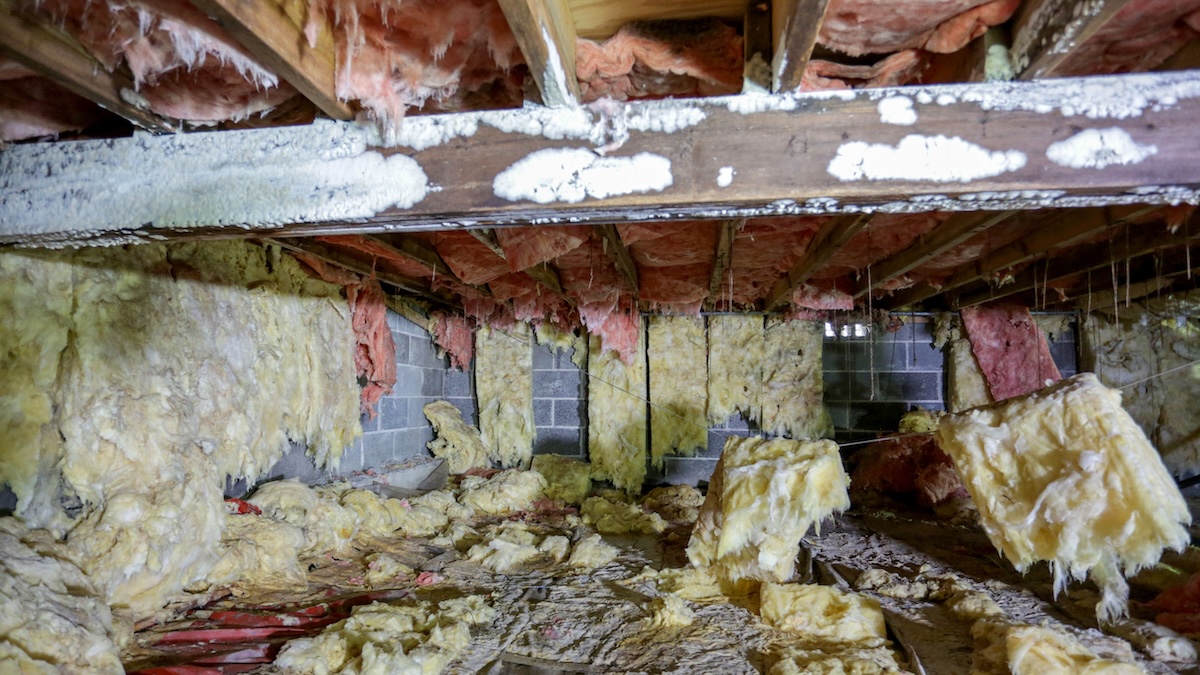 A sagging and deteriorated house foundation above a crawlspace.