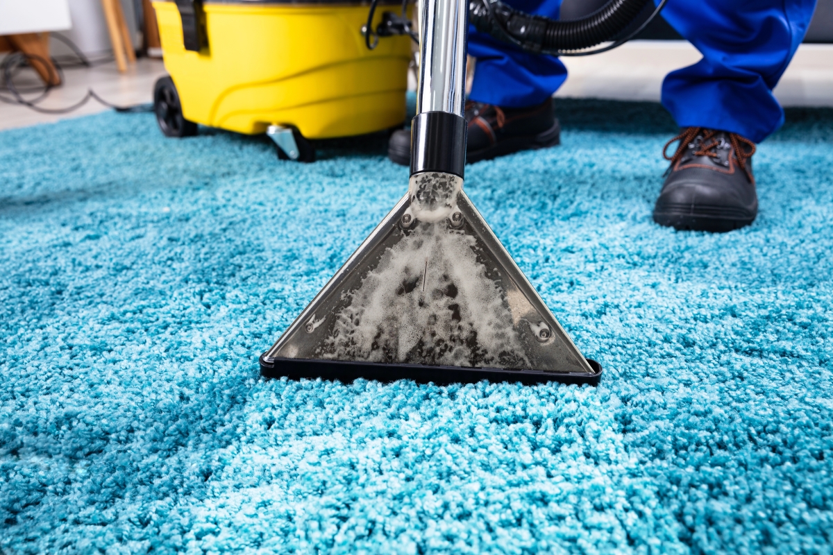 Teal carpet is being steam cleaned by a professional cleaner.