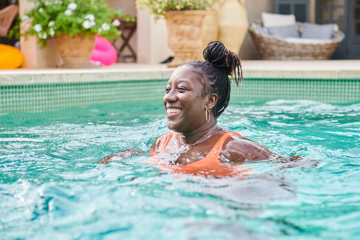 A woman is swimming in an inground pool with her head above the water.