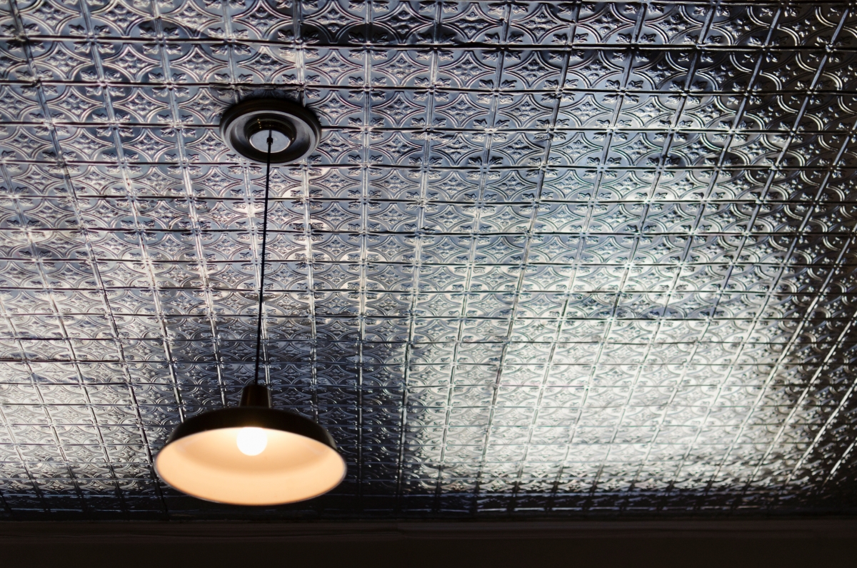 A dark tiled ceiling with a hanging light.