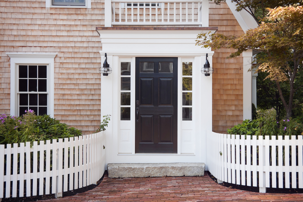 A brick home has a black steel door with windows.