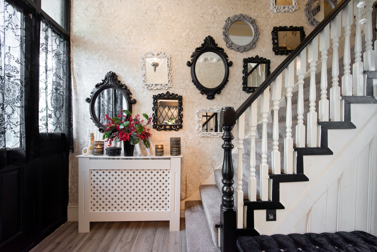 A wall next to the staircase is decorated with many antique mirrors.