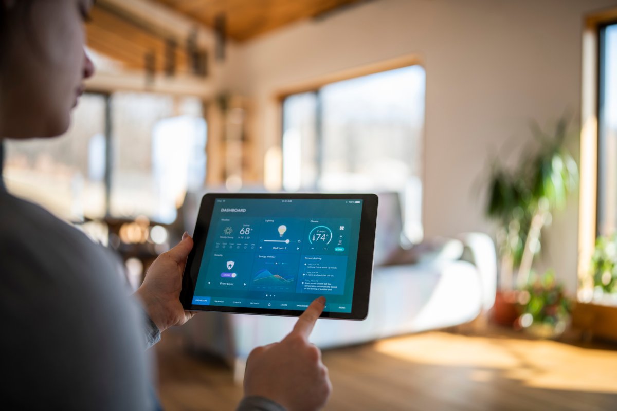 A person at home using tablet with smart home control functions.