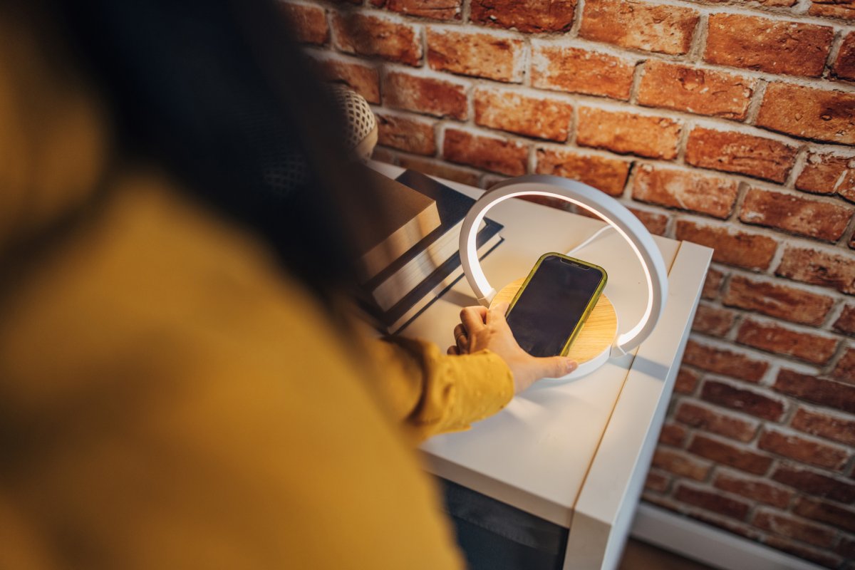 A person placing a phone on a wireless charging side table.