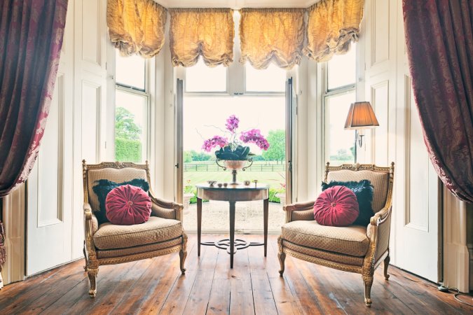 Two arm chairs by large window.