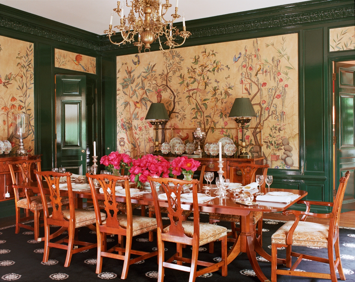 A traditional dining room with decorative wall paper and green trim.