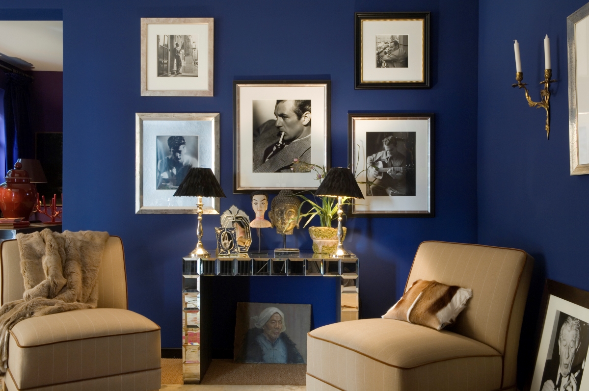 A blue painted wall with multiple framed black and white photos.