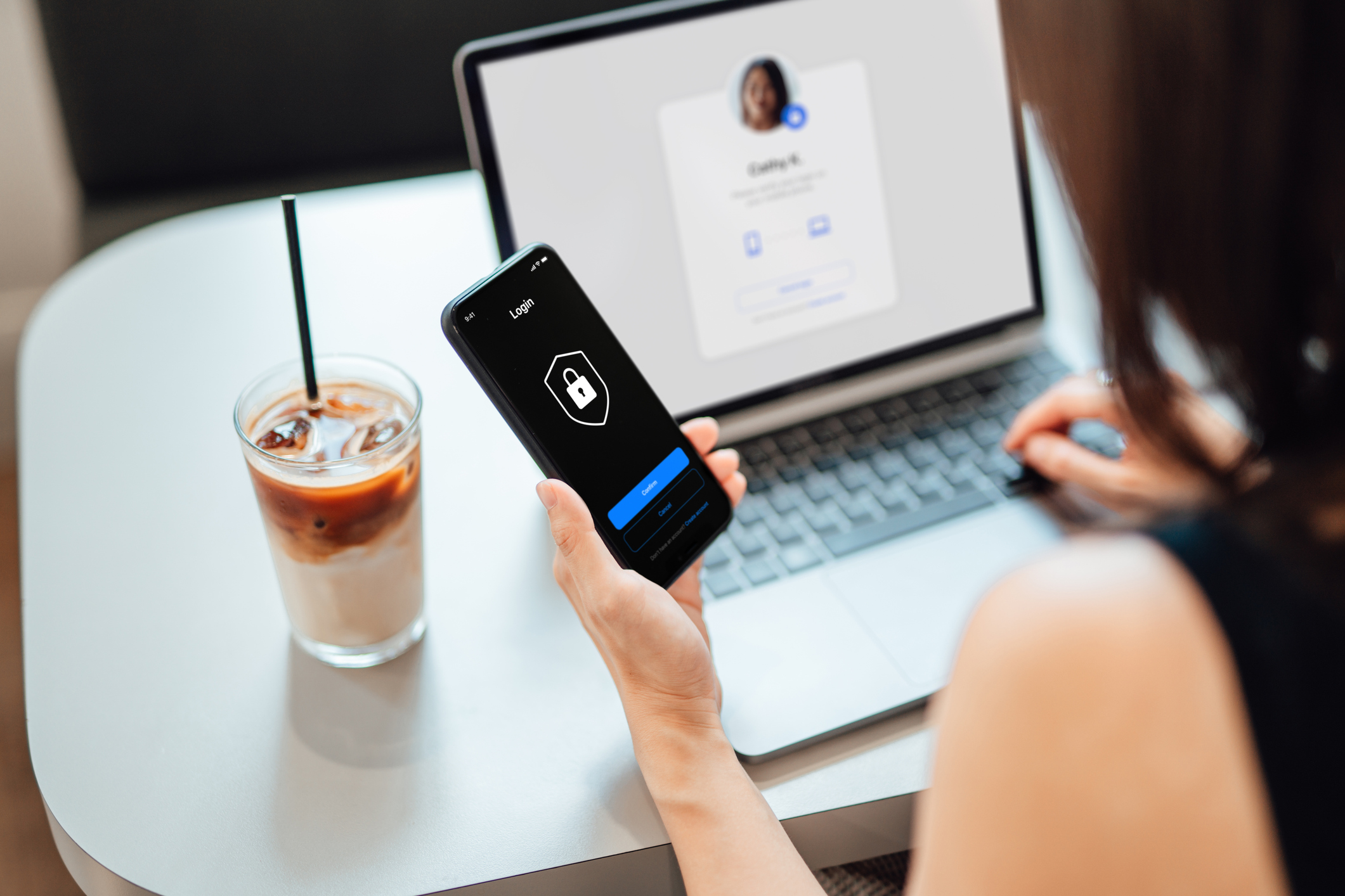 A woman uses a two-factor authentication system on her smartphone while browsing a Facebook-like website on her laptop.