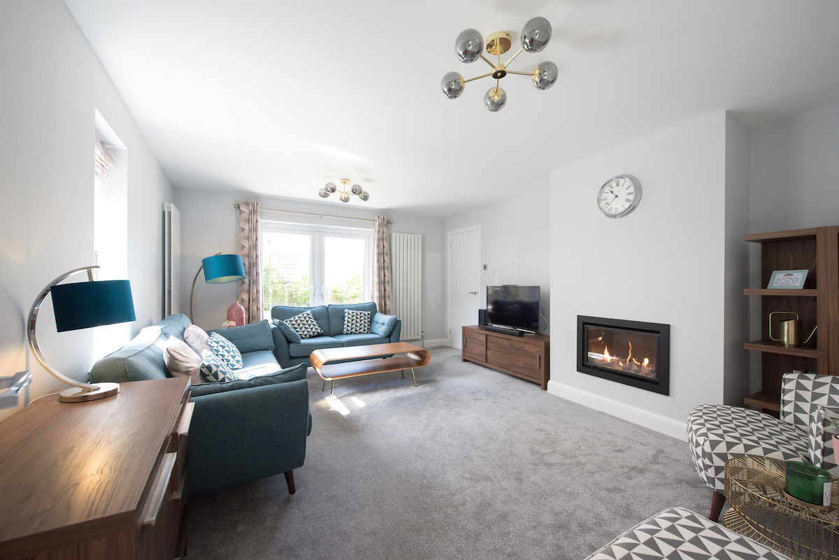 A living room with retro furniture and decorations features an electric fireplace inserted in the wall.