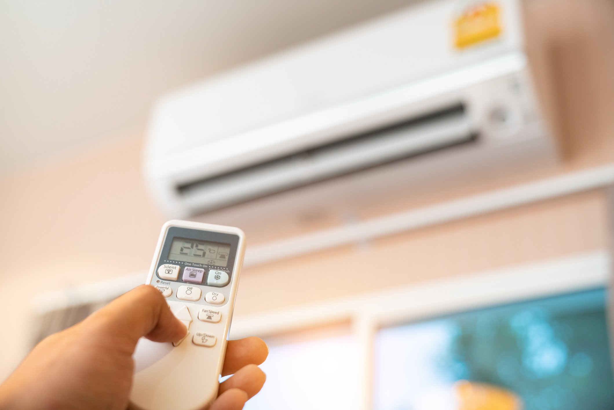 Person's hand turning off air conditioner in room.