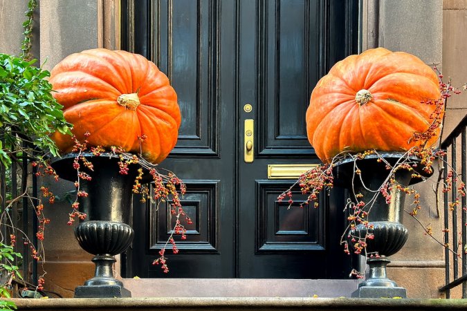 Large pumpkins and spooky plants in containers outside a front door.