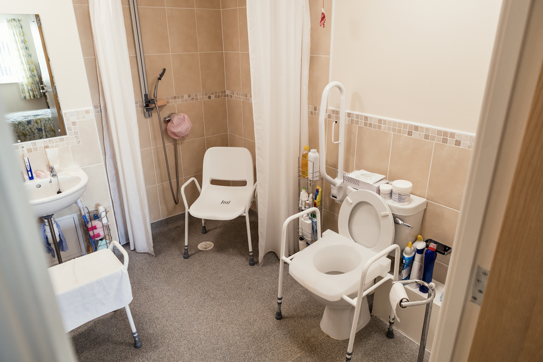 Accessible bathroom with grab bar, shower seat, and raised toilet seat.