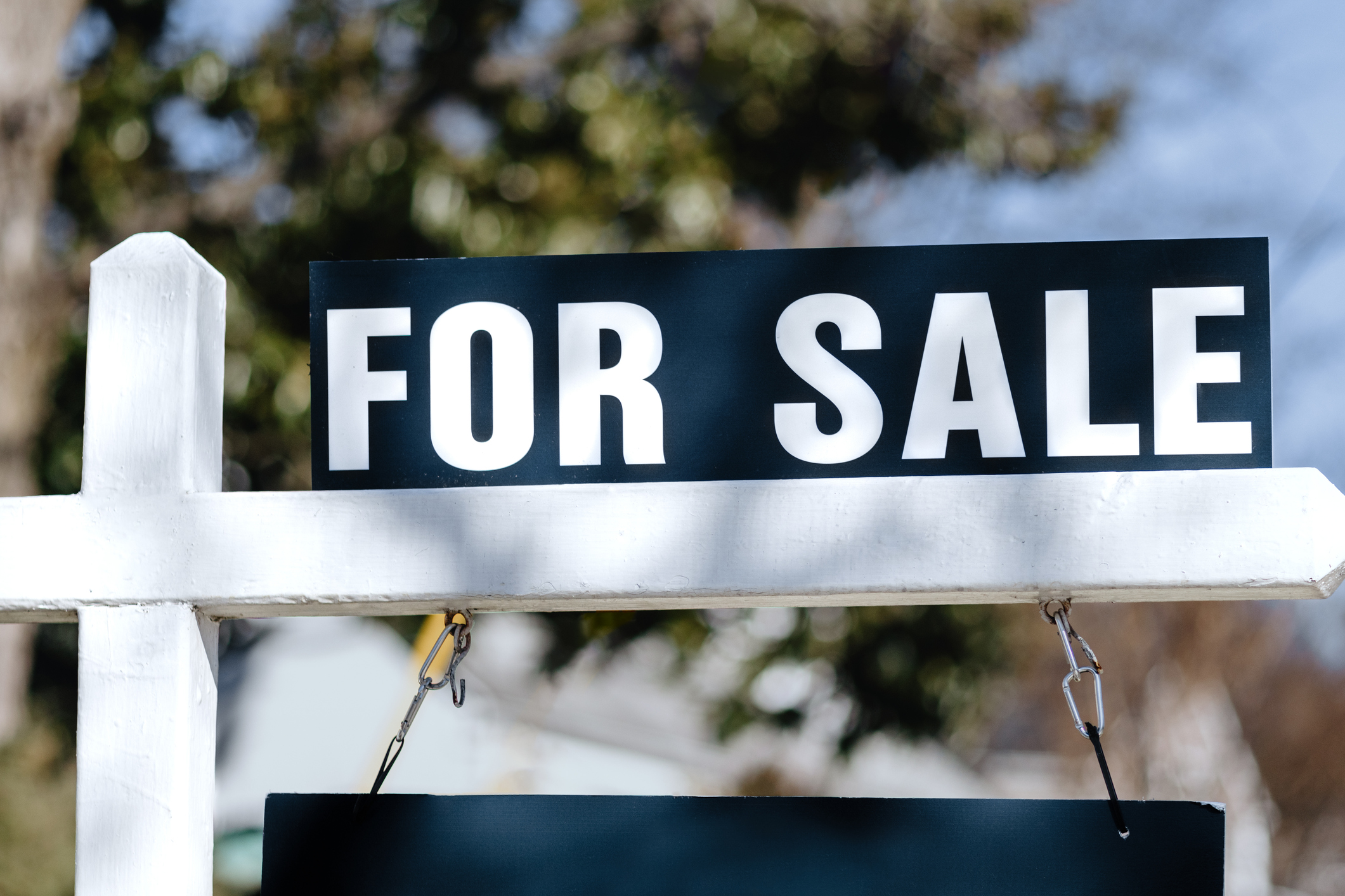 A navy-blue "for sale" sign hangs from a freshly placed white post.